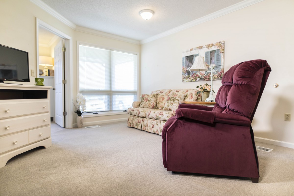 A cozy living room featuring a floral-patterned sofa and a burgundy armchair.