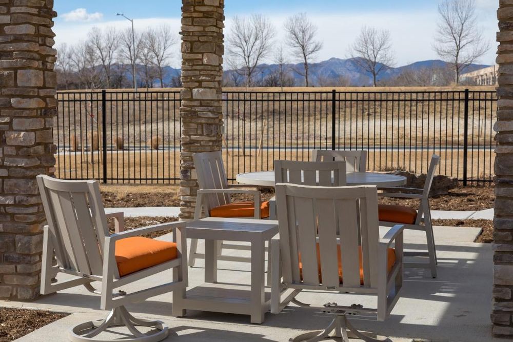 A cozy outdoor patio area with wooden furniture against a scenic mountain backdrop.