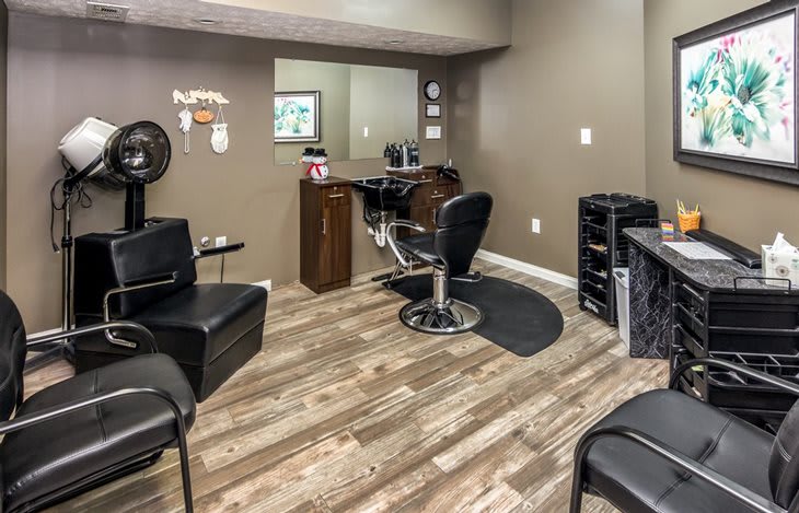 A modern hair salon interior with a styling chair, mirror, and salon equipment on a wooden floor.