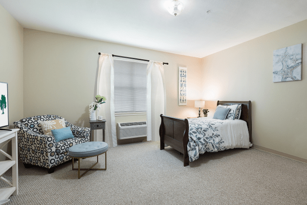 A cozy bedroom with a comfortable bed, stylish chair, and soft lighting.
