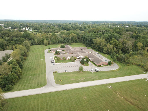 Aerial view of a building surrounded by well-maintained greenery and a parking lot.