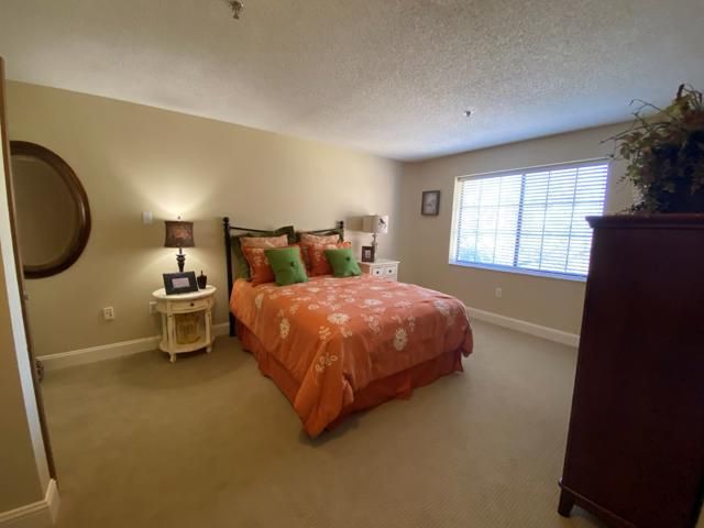 A cozy bedroom with a bed, bedside tables, and a large window.