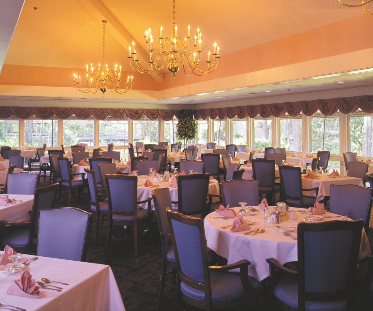 An elegant dining room with chandeliers and neatly arranged tables and chairs.