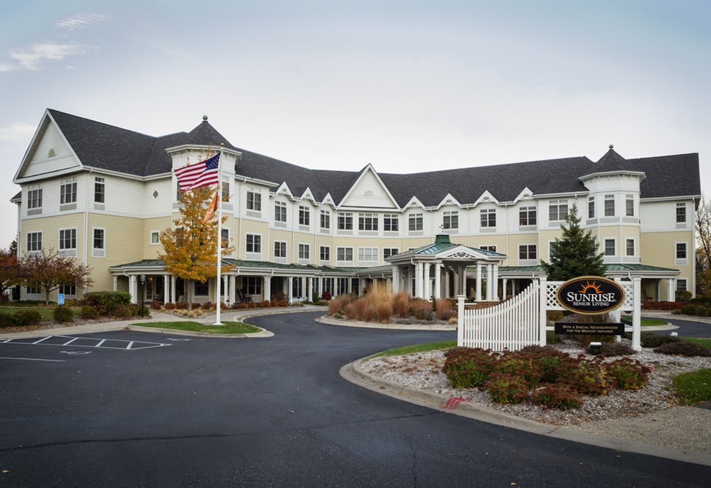 A hotel building with a landscaped entrance and an American flag.
