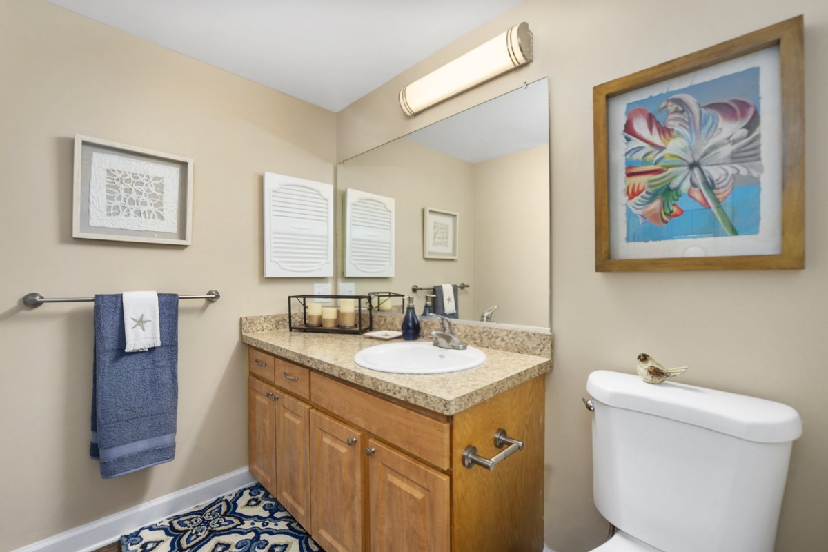 A neatly arranged bathroom with a wooden vanity, large mirror, and modern decor.