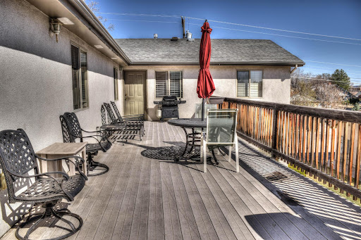 A cozy outdoor deck area with seating, a table, and an umbrella for shade.