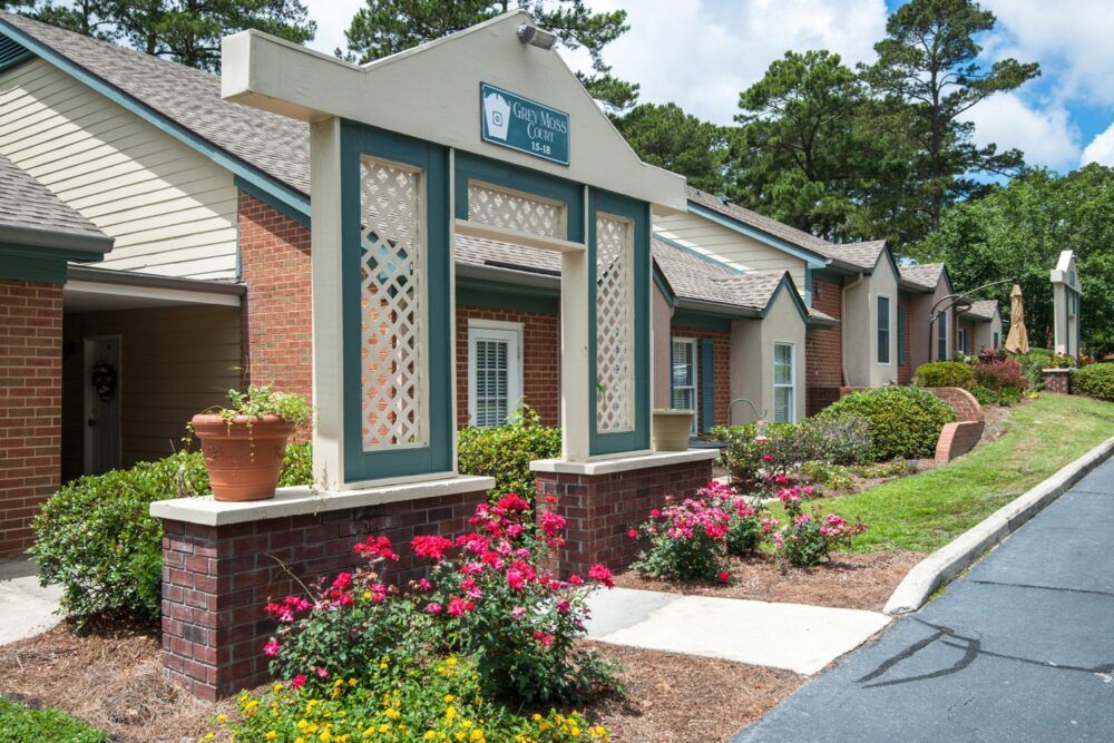 A well-maintained apartment entrance with attractive landscaping and blooming flowers.