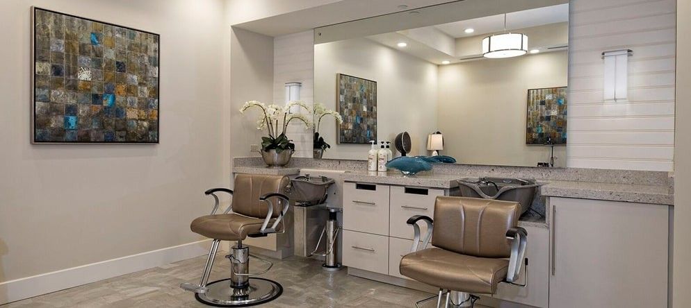 A modern beauty salon interior with chairs and a large mirror.