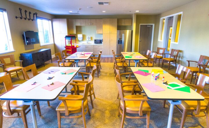 A classroom setting with tables and chairs arranged for an arts and crafts activity.