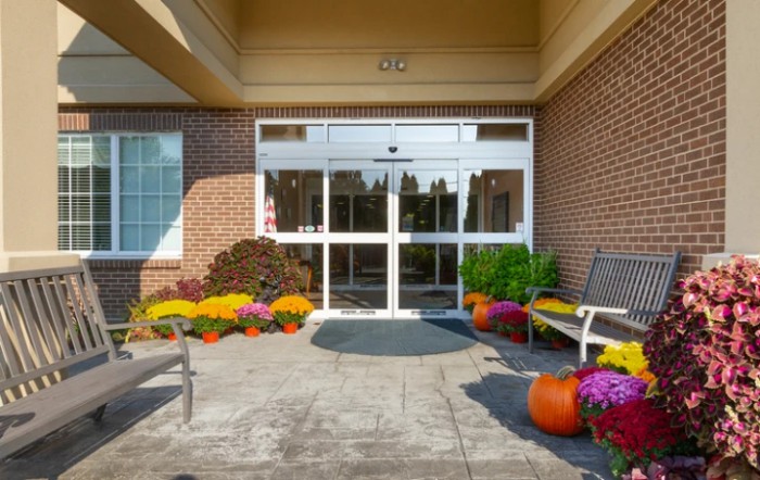 A building entrance decorated with colorful flowers and pumpkins for autumn.