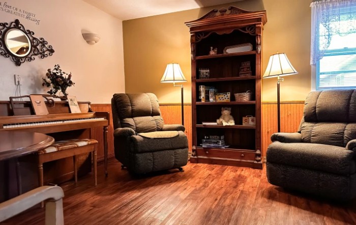 A cozy living room with comfortable armchairs, a bookshelf, and warm lighting.