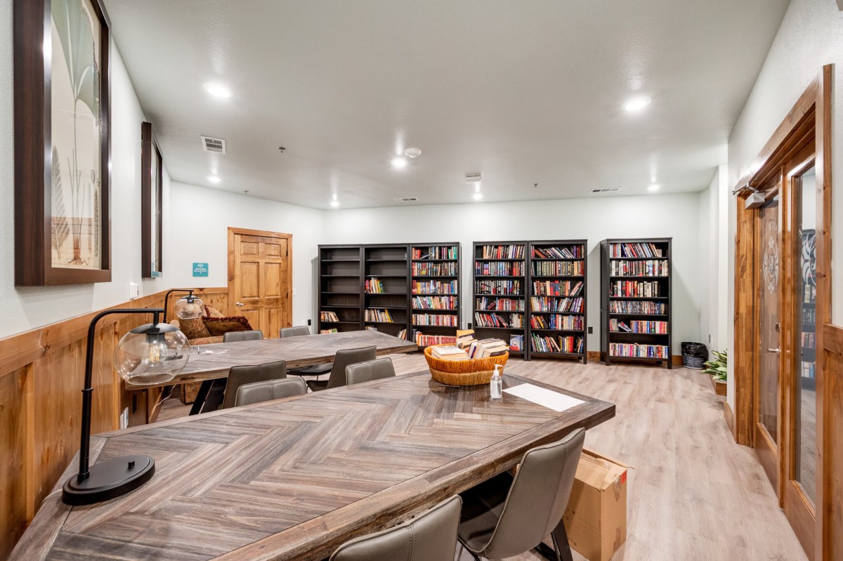 A cozy library room with bookshelves, a large table, and comfortable seating.