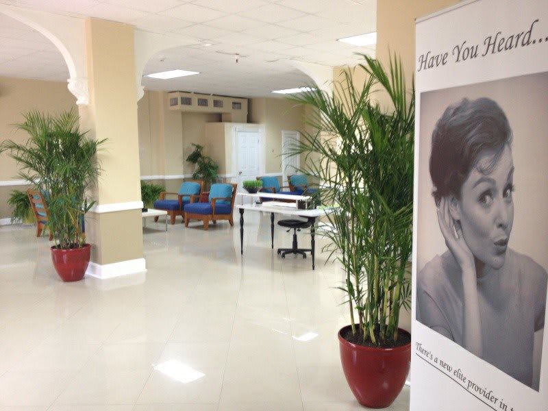 A quiet waiting area with seating, potted plants, and a large poster in the corridor.