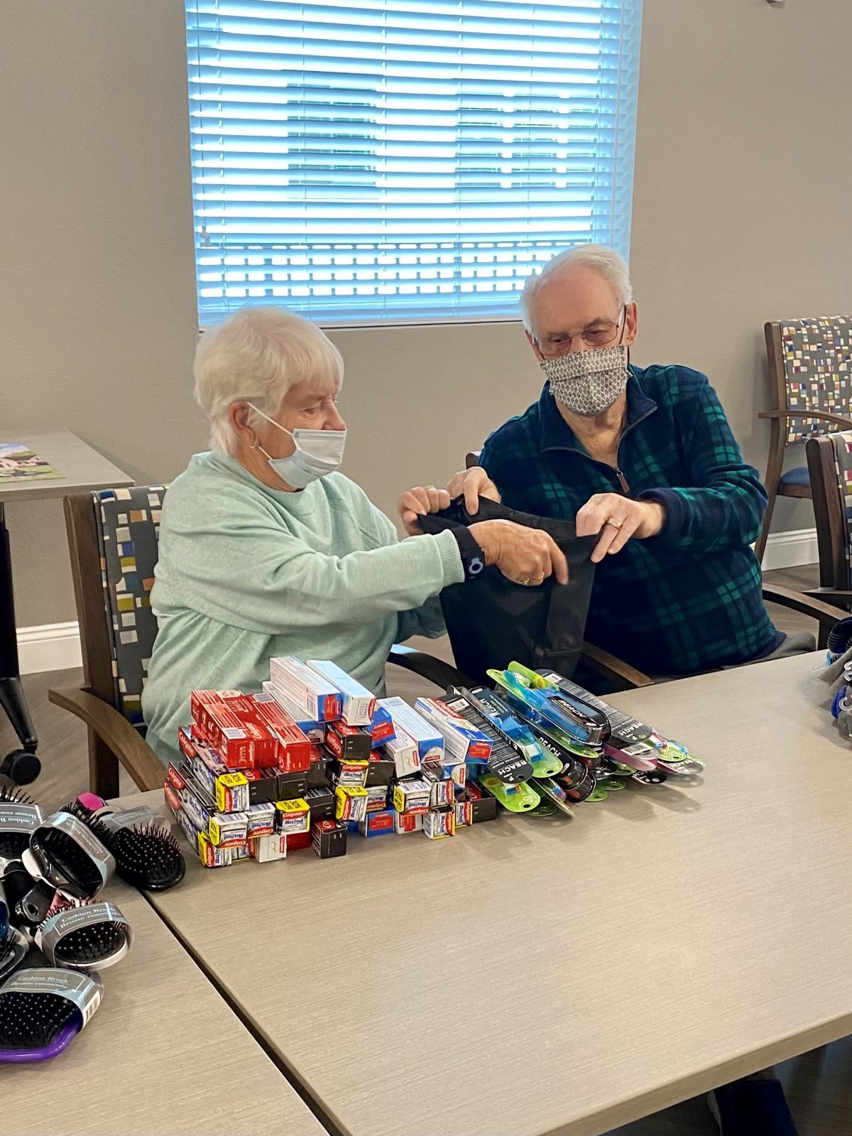 Elderly volunteers preparing donated gifts for the community.
