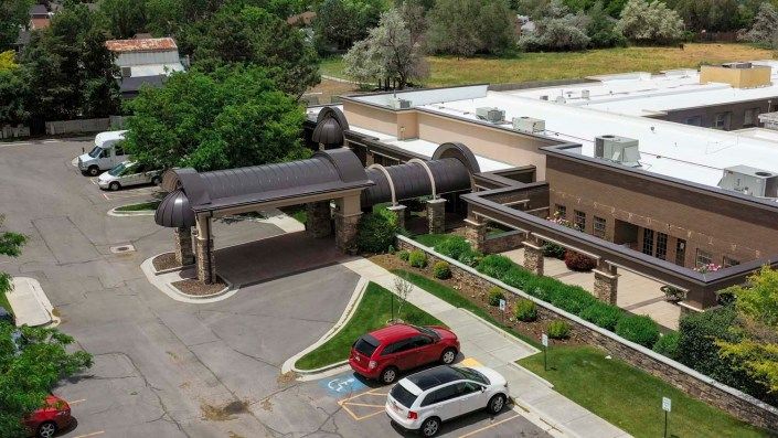 Aerial view of a building with an adjacent parking lot and surrounding greenery.