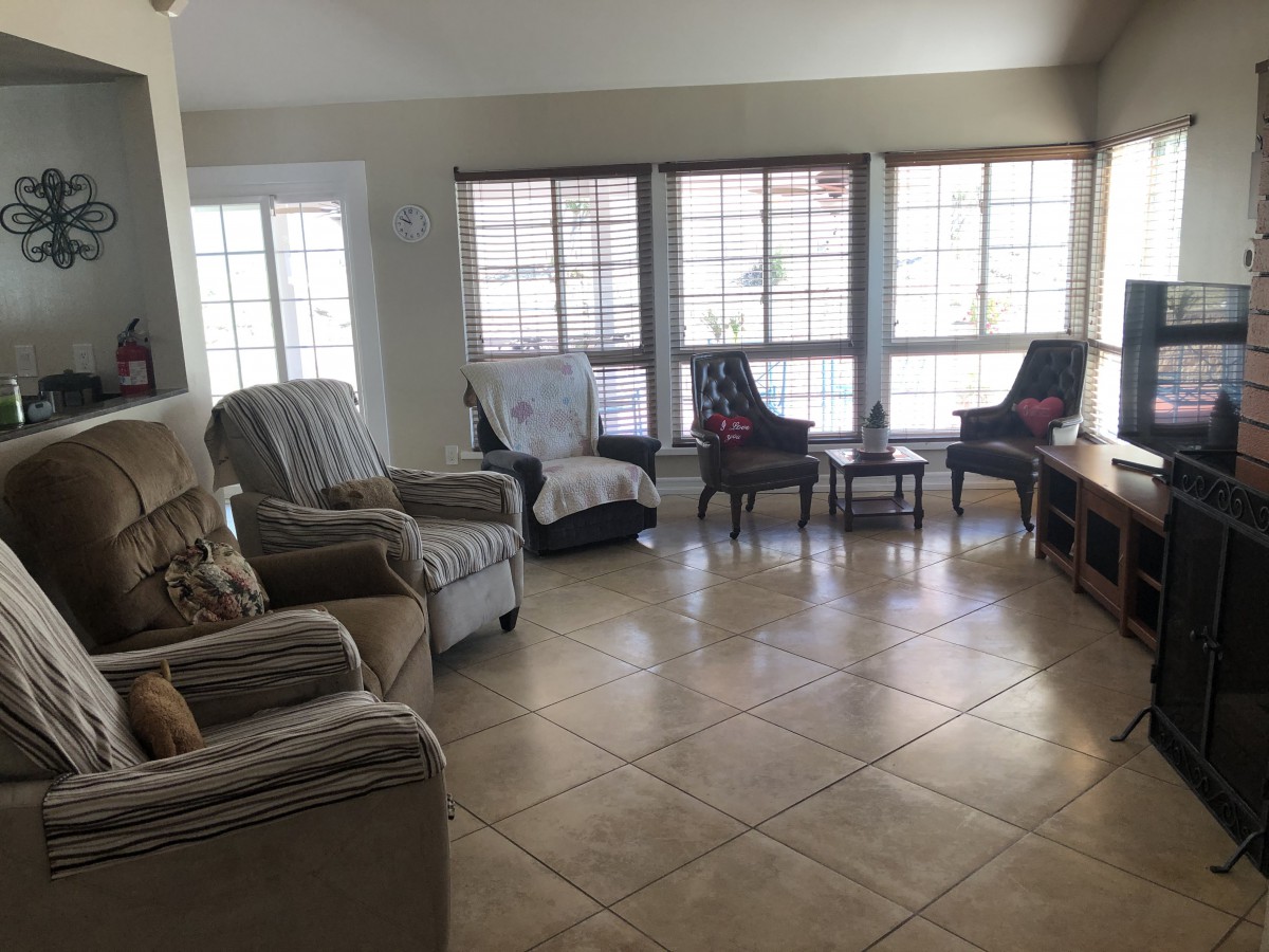 A bright living room with multiple chairs and large windows letting in natural light.