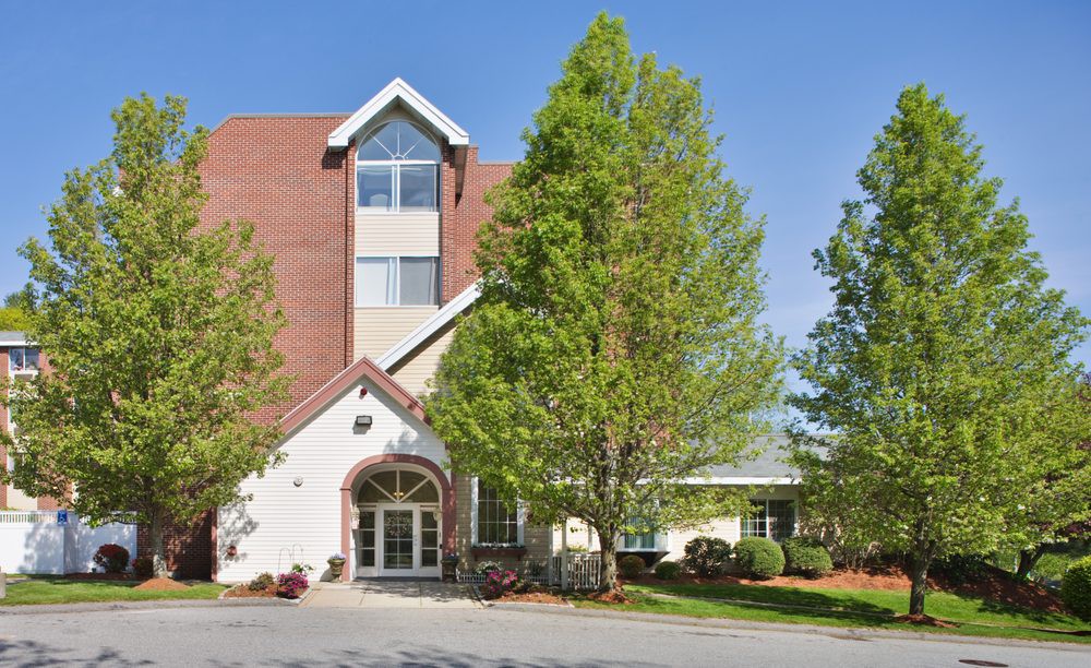 A view of a multi-story building with an entrance surrounded by trees.
