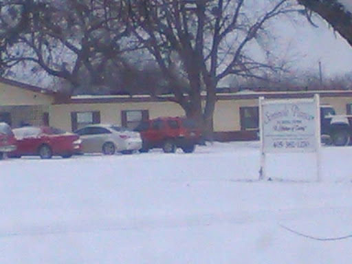 A snowy scene featuring parked cars in front of a building.