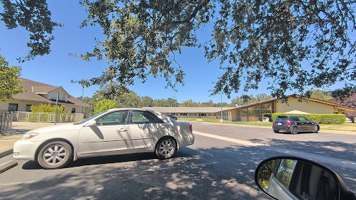 A white car parked on a sunny day, with a clear blue sky and a building in the background.