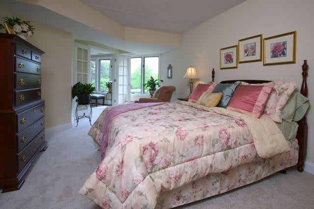 A cozy bedroom with a floral bedspread, abundant natural light, and tasteful decor.