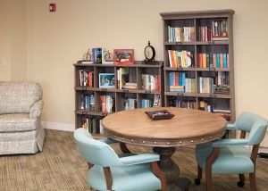 A cozy reading area with a round table, chairs, and bookshelves filled with books.