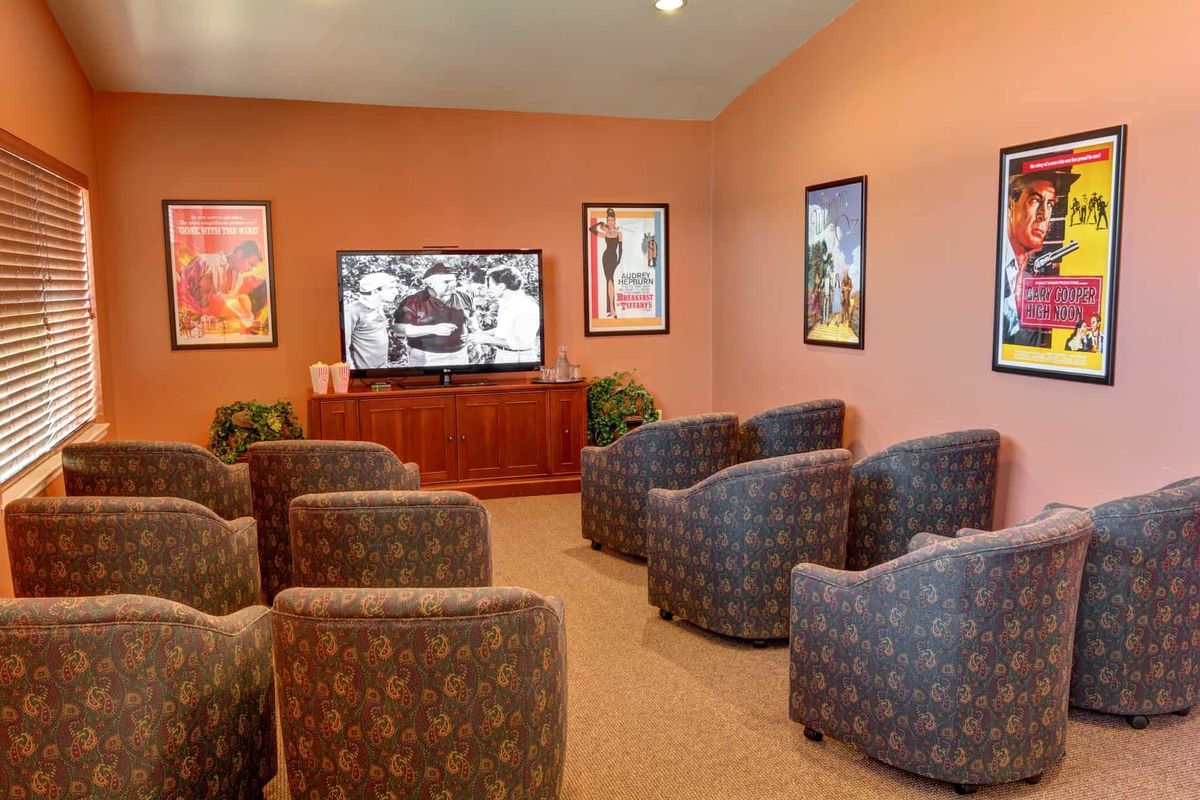 A cozy waiting room with patterned chairs facing a television, surrounded by framed artwork.
