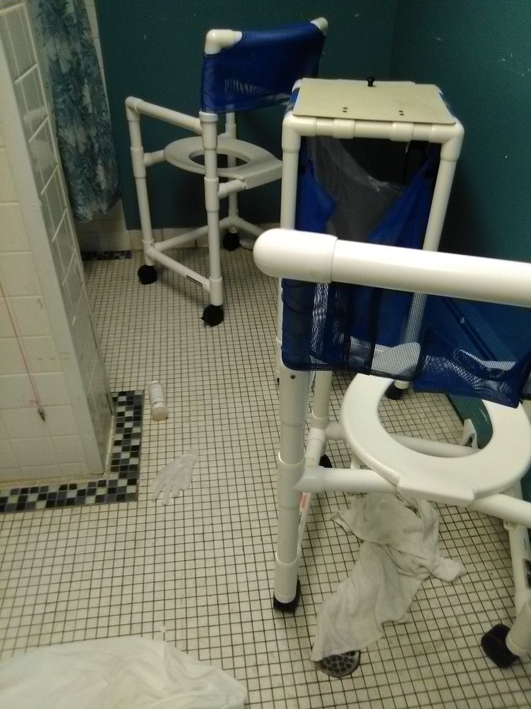 An accessible bathroom with shower chairs and tiled flooring.