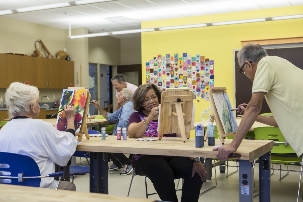 A group of people engaged in painting during an art class, each working at individual easels.