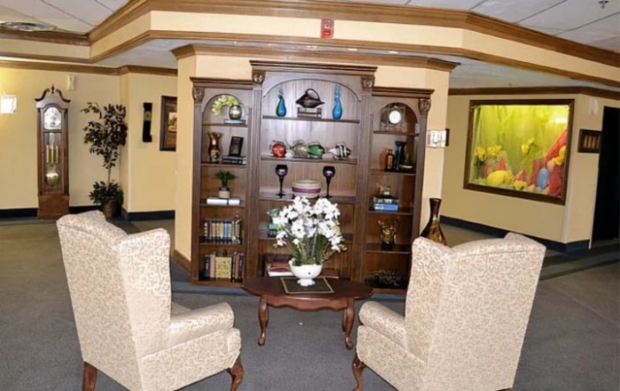 A cozy living room with a wooden bookshelf, decorative items, and comfortable armchairs.