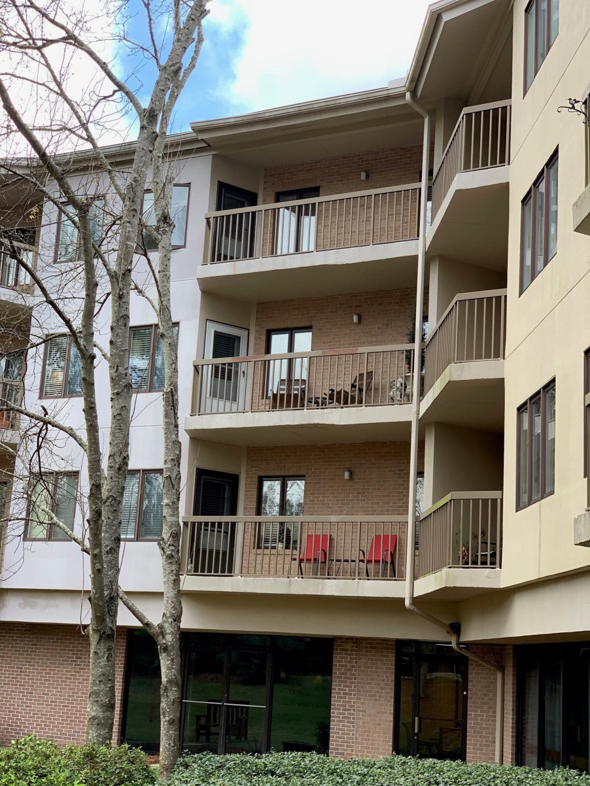 A view of an apartment building with multiple balconies, each adorned with outdoor furniture and surrounded by trees.