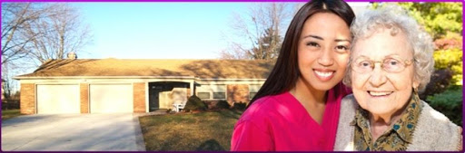 A woman in pink scrubs smiles warmly in an outdoor setting, illuminated by sunlight.