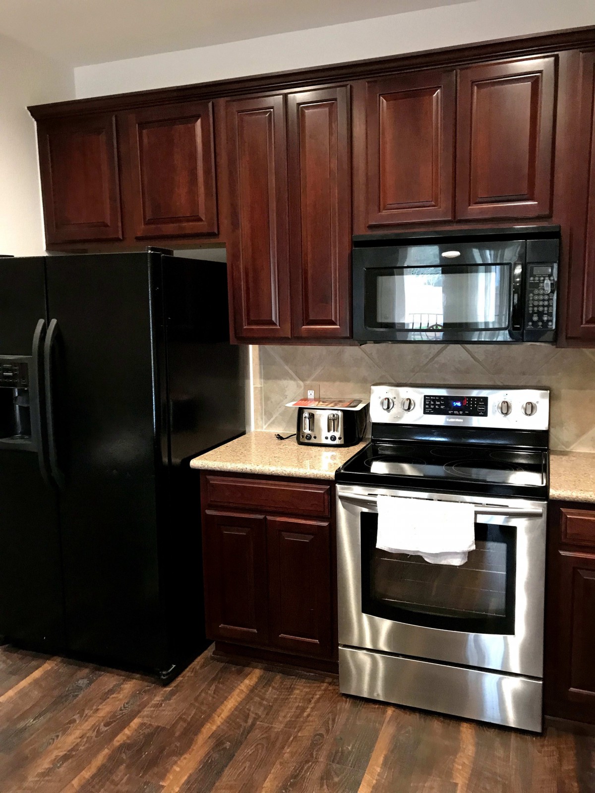 Modern kitchen with dark wooden cabinets and stainless steel appliances.