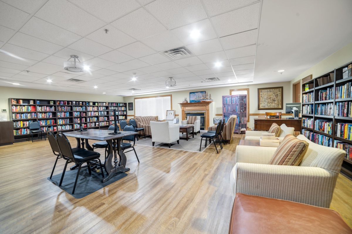 A cozy library lounge with seating areas, bookshelves, and a fireplace.