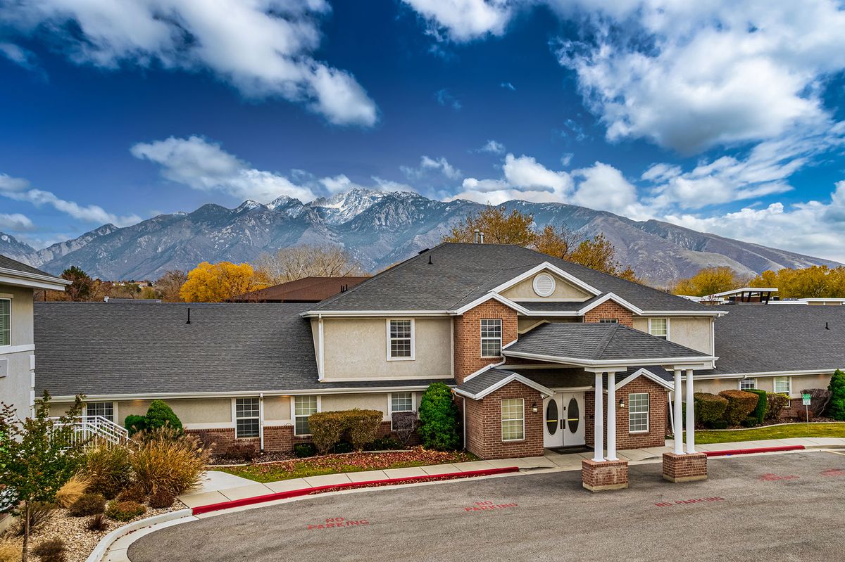 A residential building with a mountainous backdrop under a partly cloudy sky.
