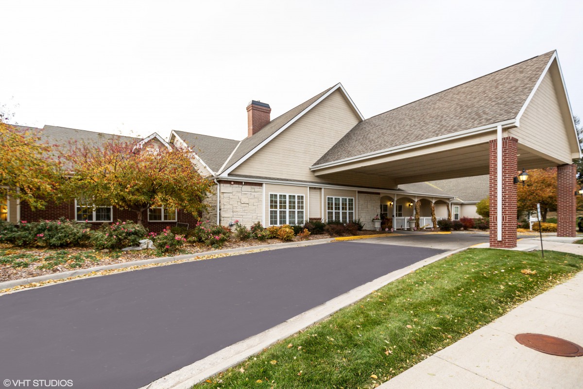 A suburban residential building with a covered driveway and landscaping.
