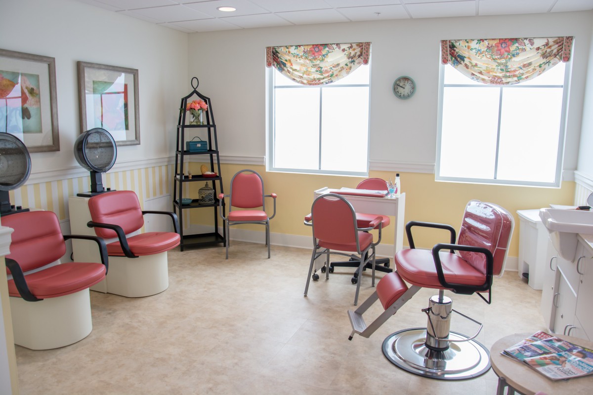 A cozy salon interior with red chairs, mirrors, and styling equipment.
