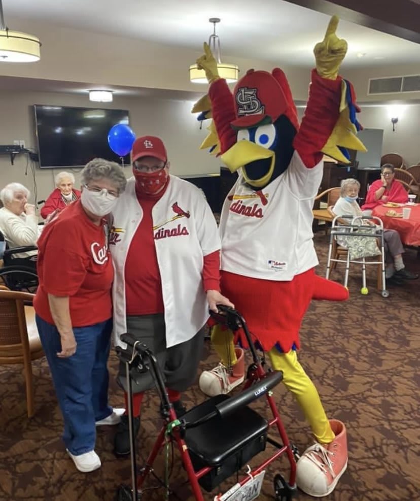 A group photo with a sports mascot at an indoor gathering.