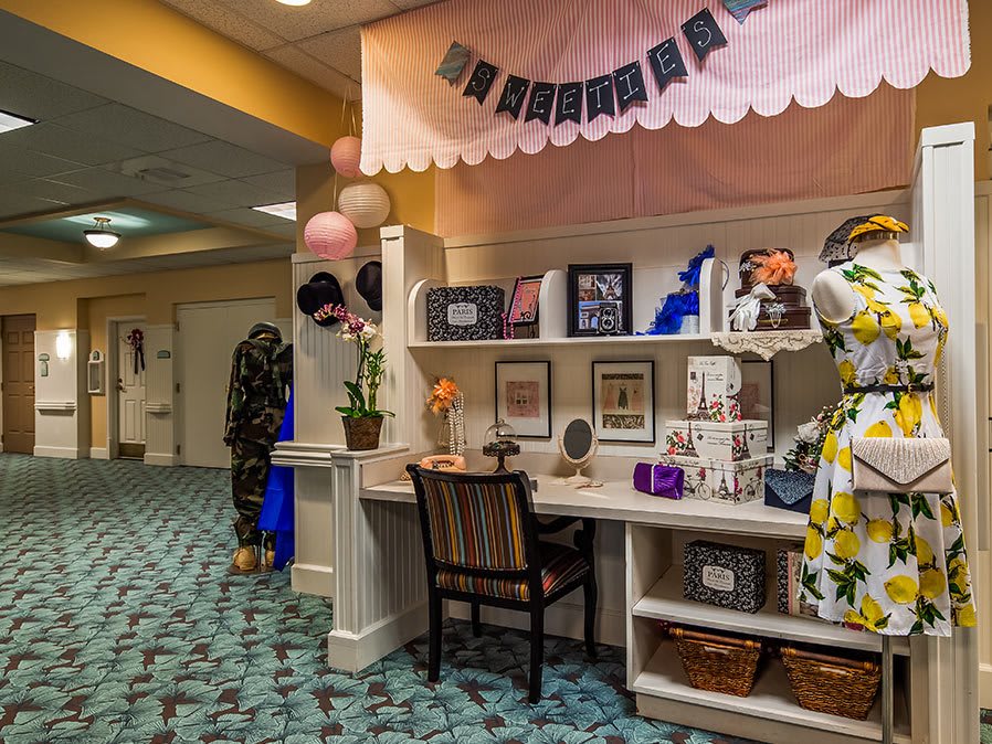 A charming boutique interior showcasing a variety of gifts and decor, with a mannequin in a floral dress and festive balloons.