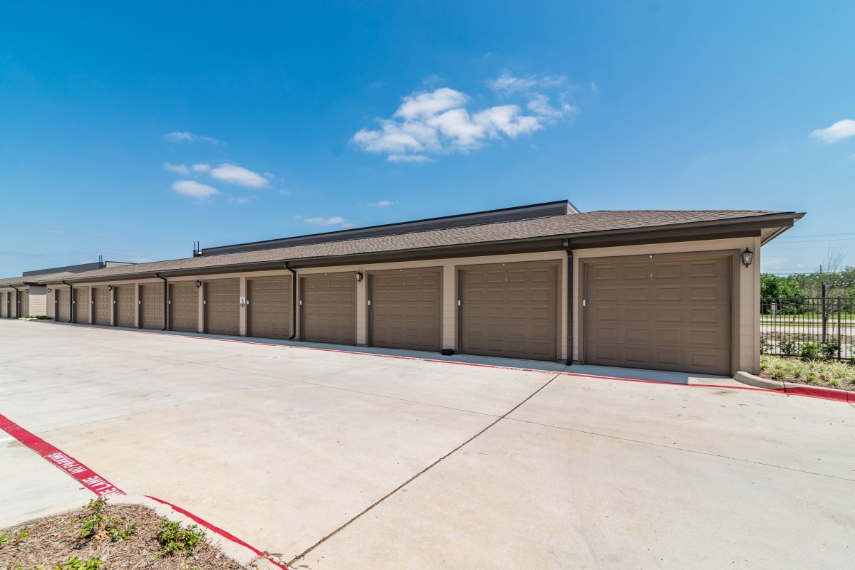 Row of garages with closed doors under a clear blue sky.