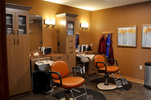 A modern barber shop interior featuring orange chairs and well-organized workstations.