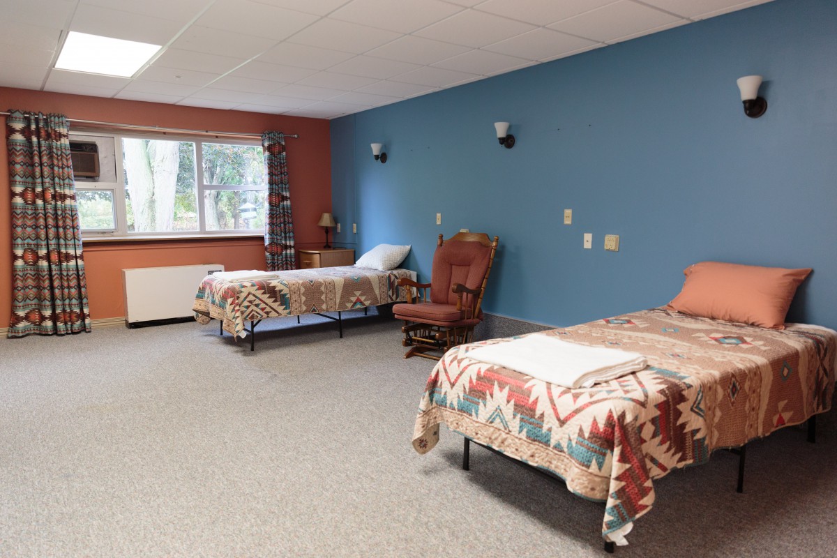 A cozy bedroom with two beds, featuring colorful walls and a large window.