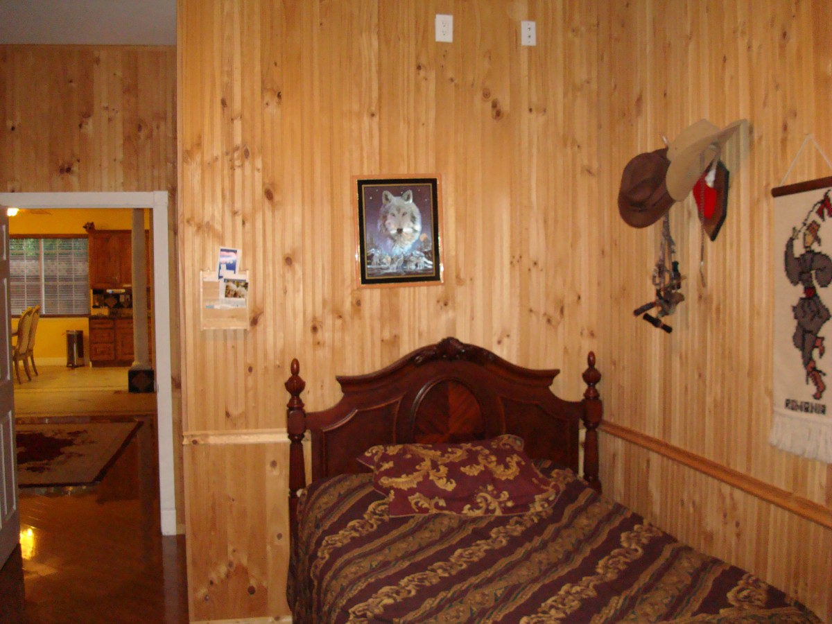 A cozy bedroom with wood paneling and rustic decor, featuring a single bed.