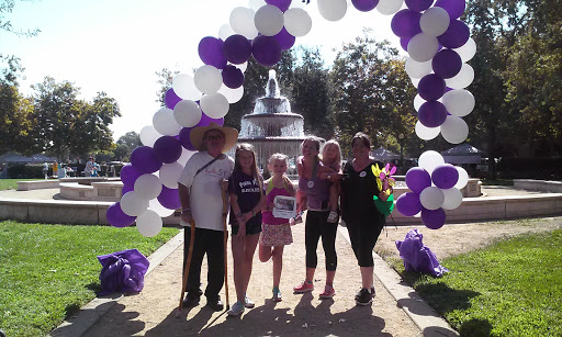 A group of five people enjoying a sunny day at a park event under a decorative balloon arch.