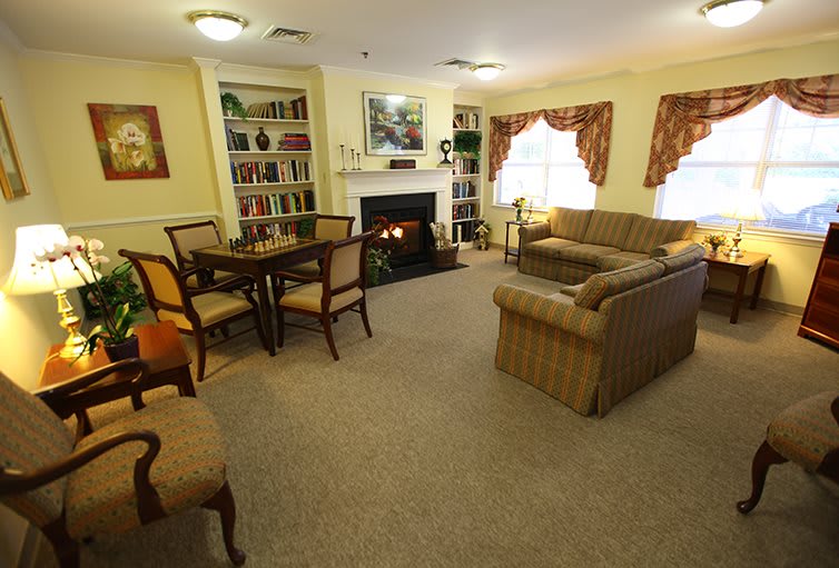 A cozy living room interior with a sofa, chairs, table, and a fireplace.
