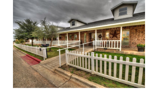 A charming house with a welcoming porch and white picket fence under a cloudy sky.
