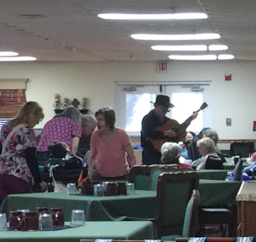 A lively music performance taking place in a dining area with seniors enjoying the entertainment.