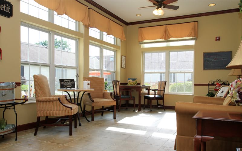 A cozy living room with large windows, comfortable chairs, and ample natural light.