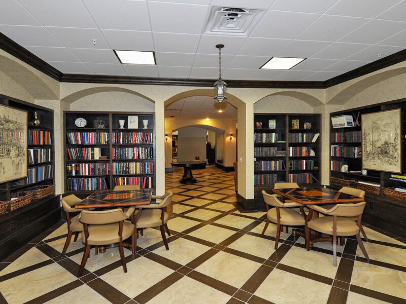 A cozy library space with tables and chairs surrounded by shelves filled with books.