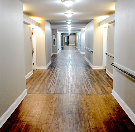 A well-lit corridor featuring wooden flooring and doors along the walls.