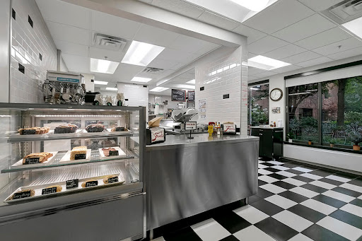 A modern restaurant kitchen featuring a stainless steel counter and a display case for food items.